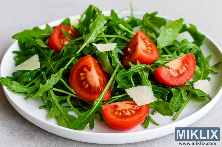 Fresh arugula salad with tomato wedges and Parmesan cheese on a white plate