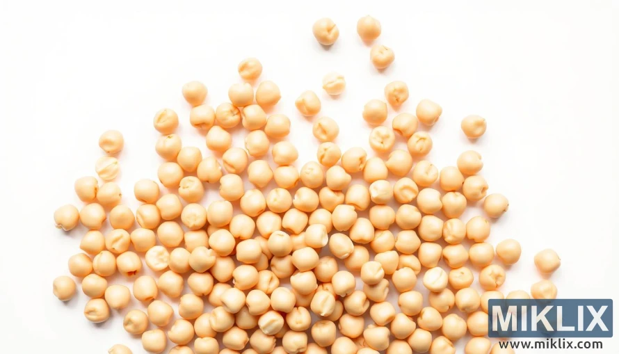 A close-up shot of an assortment of chickpeas against a clean, white background. The chickpeas are arranged in a symmetrical pattern, with a few scattered across the frame. The lighting is soft and diffused, creating a warm, inviting atmosphere. The focus is sharp, highlighting the intricate texture and subtle variations in color of the individual chickpeas. The overall composition conveys a sense of order, cleanliness, and attention to detail, suggesting the importance of proper handling and preparation when consuming chickpeas.