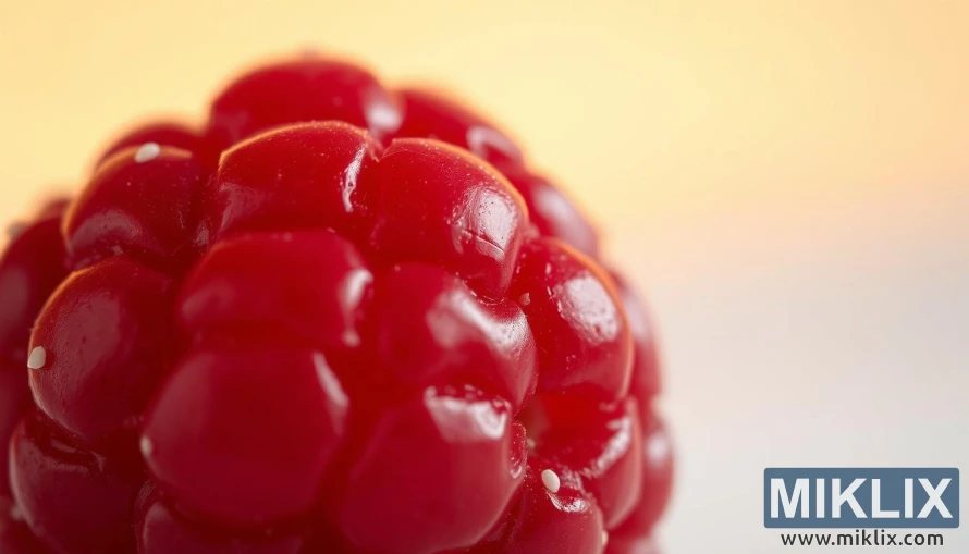 A close-up view of a vibrant, juicy raspberry, its shiny surface reflecting the soft, diffused lighting. The raspberry's deep red hue is accentuated, with delicate white seeds dotting the surface. In the background, a blurred, pastel-toned backdrop suggests a natural, organic setting, evoking a sense of freshness and purity. The image is captured with a shallow depth of field, drawing the viewer's attention to the intricate details of the raspberry's structure and texture. The overall tone is warm, inviting, and visually appealing, highlighting the essence of the raspberry ketone supplement.